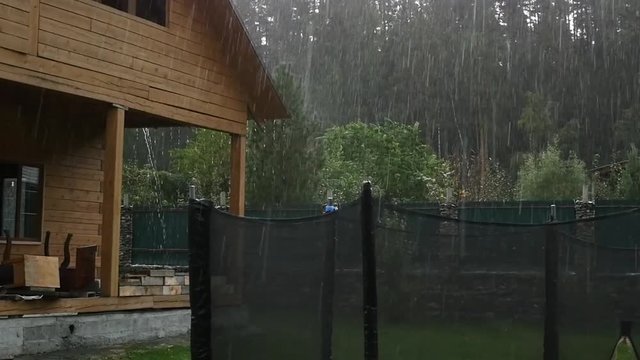 Heavy rain shower in backyard at unfinished house. slow motion