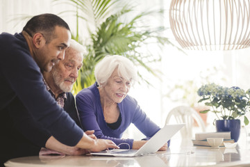 Man helping senior couple set up laptop