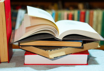 Open book, stack of hardback books on table. Top view.