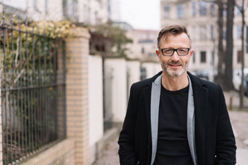 Older stylish man walking on an urban sidewalk