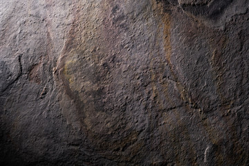 Stone texture surface background in dark taupe, liver and gold tones.