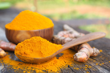 Turmeric powder in wooden spoon on old wooden table. Herbal