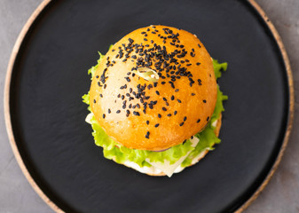 Fresh homemade burger with black sesame seeds in plate with french fries potatoes. Top view. Copy space.