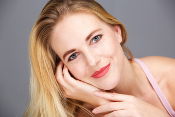 Naklejka premium Beauty portrait of happy young blond woman against gray background