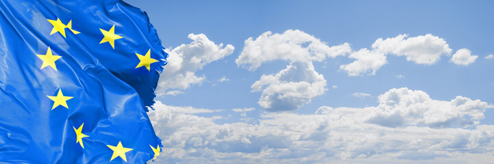 Frayed European flag on cloudy sky - concept image with copy space