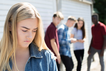 Fototapeta na wymiar Unhappy Teenage Girl Being Gossiped About By Peers