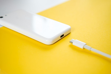 Smartphone Connects to Charger through  Cable on Yellow Background. copy Space for insert text.