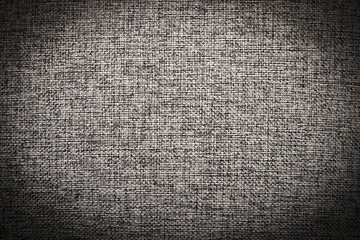 Grey textile interlaced pattern closeup, background with darkened vignette