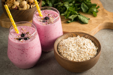 Glasses of berry smoothie with nuts, mint, blueberry, blackberry, raspberry, and yogurt on wooden table. Weight loss and diet concept. 