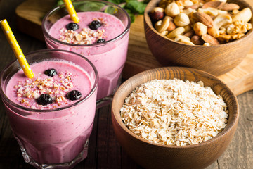 Glasses of berry smoothie with nuts, mint, blueberry, blackberry, raspberry, and yogurt on wooden table. Weight loss and diet concept. 
