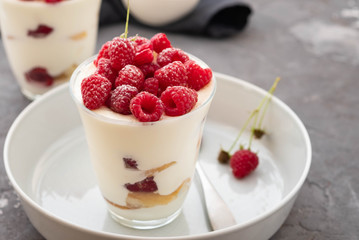 Tiramisu with raspberry in glasses on grey background. Italian dessert. Copy space.