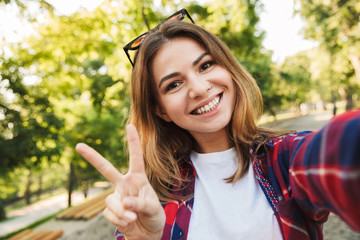 Beautiful woman student walking in the park take a selfie by camera.
