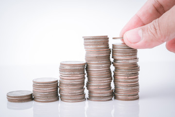 saving money, hand putting money coin stack on white background