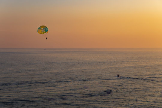 Mediterranean sea and a motor boat with a parachute in Dubrovnik, Croatia - sunset orange light