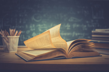 School books on desk formulas and Physics inscription on the blackboard , education concept