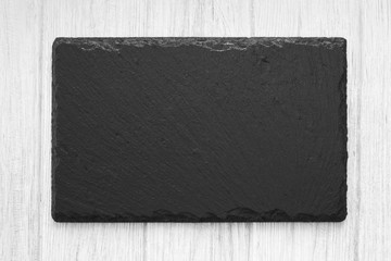 White painted wooden table background with natural shale stone plate empty board