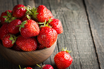 Macro photo of fresh ripe red strawberry in a wooden bowl on rustic background. Organic natural products.