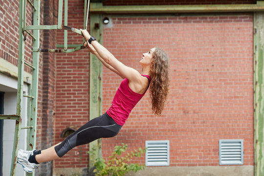 Sportliche junge Frau klettert auf einer Leiter