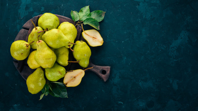 Fresh pears on a black stone table. Fruits. Free space for text. Top view.