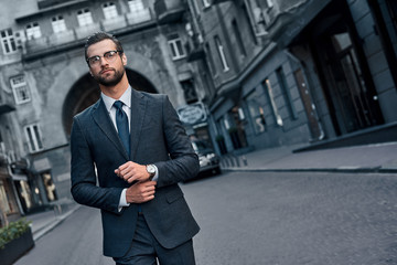 Confident and handsome. Full length of young man in full suit smiling while walking outdoors