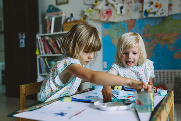 Fototapeta premium Portrait of happy adorable little girls painting at home together.