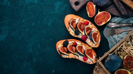 Sandwich with figs, wild berries and cheese. On the old background. Dessert. Free space for text. Top view.