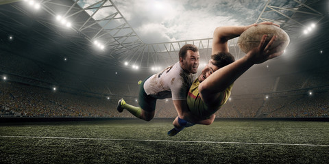 Fototapeta na wymiar Two male Rugby players fight for the ball in flight on professional rugby stadium