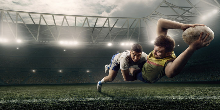 Two male Rugby players fight for the ball in flight on professional rugby stadium