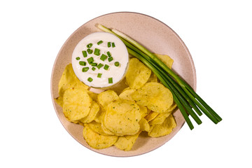 Ceramic plate with potato chips and glass bowl with sour cream isolated on a white background