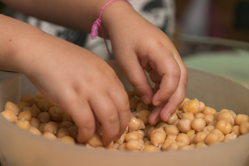 Child hands take lentils in bowl.