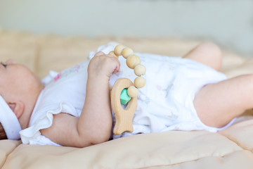 Little girl play with wooden rattle. Developing toy
