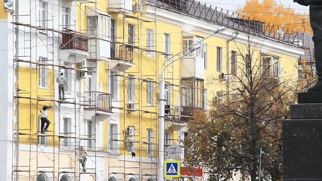 Construction workers on scaffolding repairing the five-storey classic soviet style building.