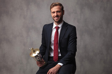 champion businessman holding his trophy cup and sits