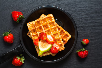 Food concept square Waffles and syrup with strawberry and fig topping in iron pan with copy space