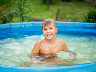 Fototapeta na wymiar Cute blond boy bathing in a small pool