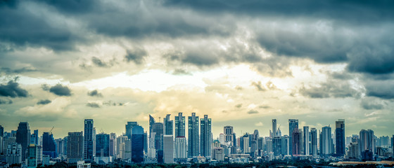 Fototapeta premium Panorama krajobrazowa sceneria budynków i drapaczy chmur w biznesowym centrum miasta Bangko z deszczową chmurą nad miastem w niebieskim odcieniu