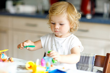 Adorable cute little toddler girl with colorful clay. Healthy baby playing and creating toys from play dough. Small kid molding modeling clay and learning