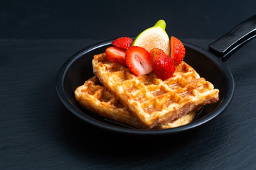 Food concept square Waffles and syrup with strawberry and fig topping in iron pan with copy space