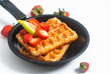 Food concept square Waffles and syrup with strawberry and fig topping in iron pan with copy space