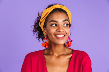 Image of charming woman 20s in hair band and earrings smiling and looking aside, isolated over violet background
