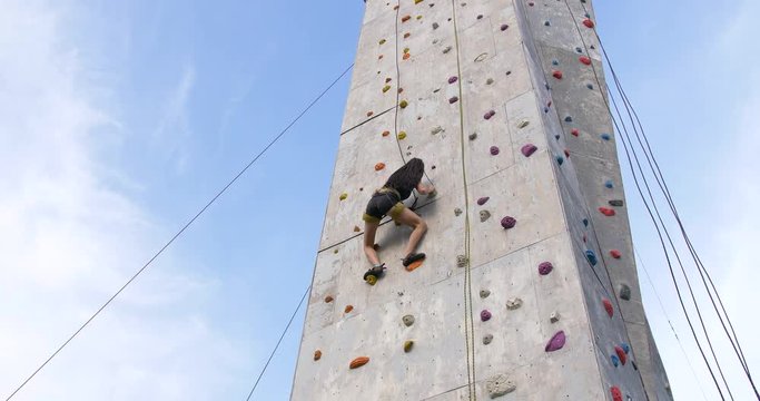 Boulder climber woman exercising at outdoor climbing gym wall