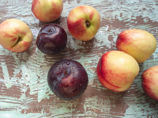 Ripe nectarines scattered in a non-wooden background red large plums