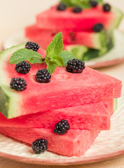Watermelon slice pie with blackberries and mint leaf on pastel yellow background.