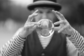 A clown man with a transparent magic ball in his hands on the street of a European city