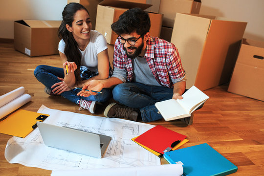 Young couple moving into a new house.They sitting on floor and calculate savings and home budget.