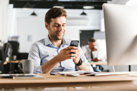 Smiling business man writing message on smartphone