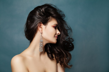 Beautiful brunette woman portrait. Sexy female model with dark curly hair and jewelry earrings