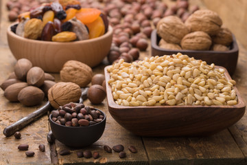 cedar nuts peeled in wooden bowl on table, grunge style.