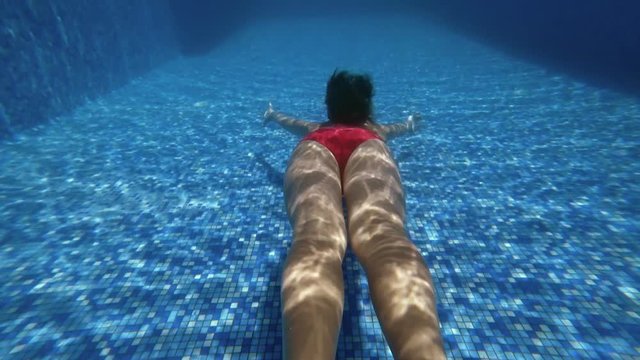 Underwater camera follow teenage girl dive in blue swimming pool. Underwater 4K shooting.