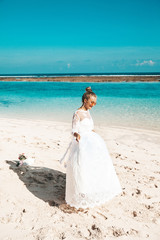Fototapeta na wymiar Portrait of beautiful bride dancing on the beach behind blue sky and sea